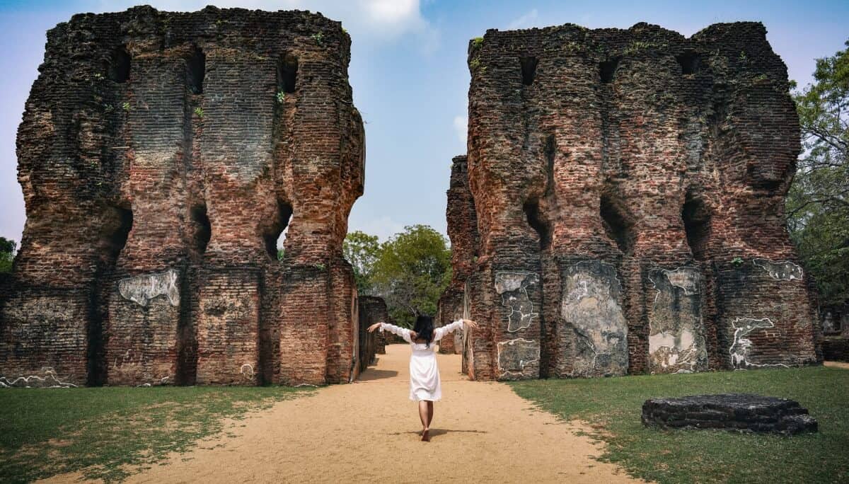 a girl walking to an opening of an ancient ruins