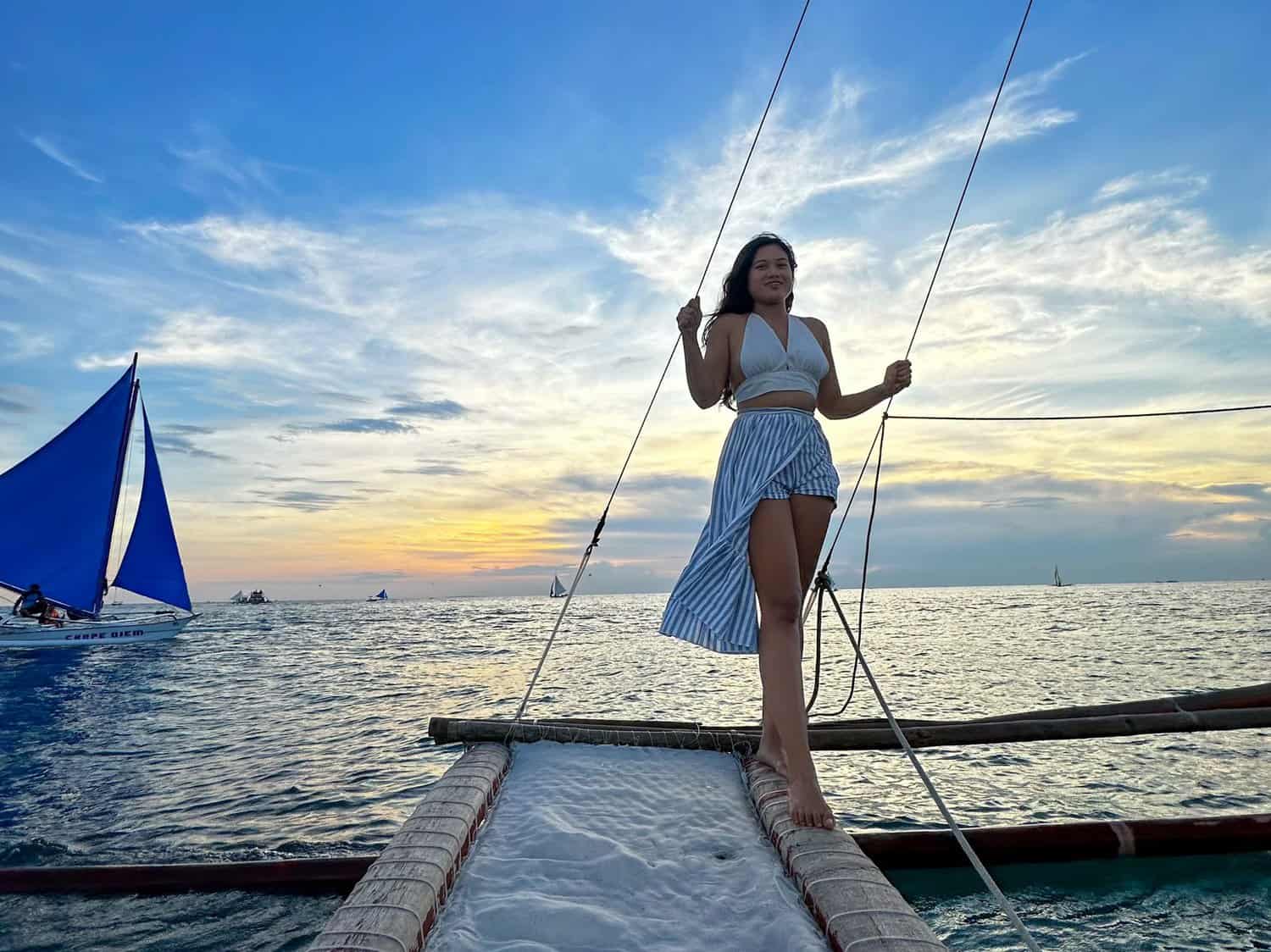 I am on a traditional Filipino paraw sailboat sailing at sunset in Boracay.