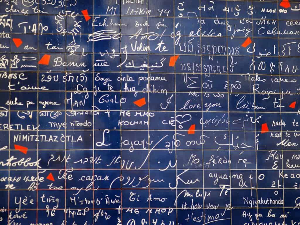 A blue wall with enameled lava tiles of different ways to say I Love You Wall around the world.