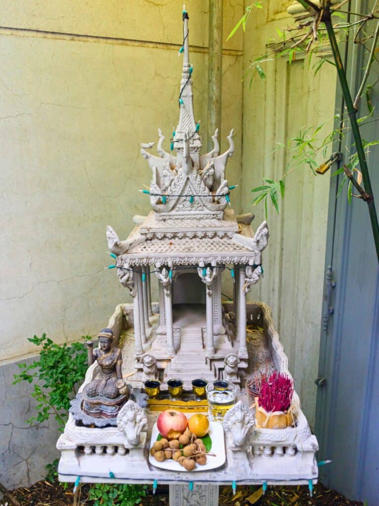 A close-up of Cambodian New Year offerings with a Buddha statue, candles, incense, and fruits, focusing on the spiritual practices of Khmer New Year 2024.