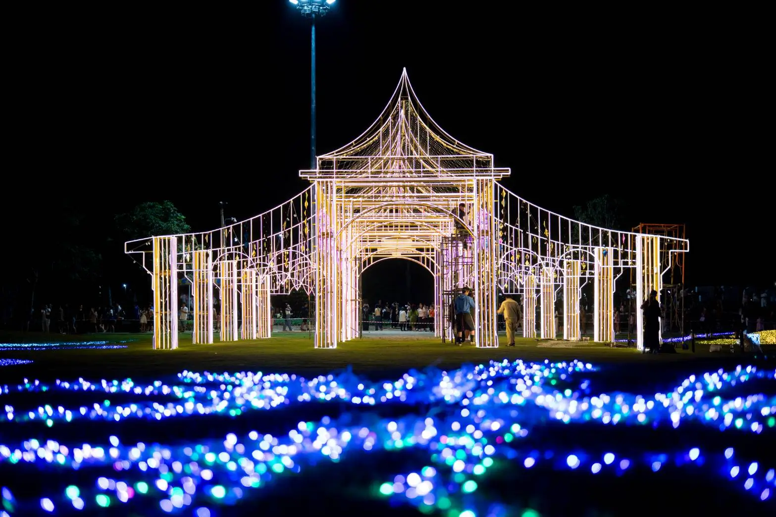 An illuminated structure resembling a traditional pavilion, set against a dark night sky during the Charming Chiang Mai Flower Festival 2024-2025 