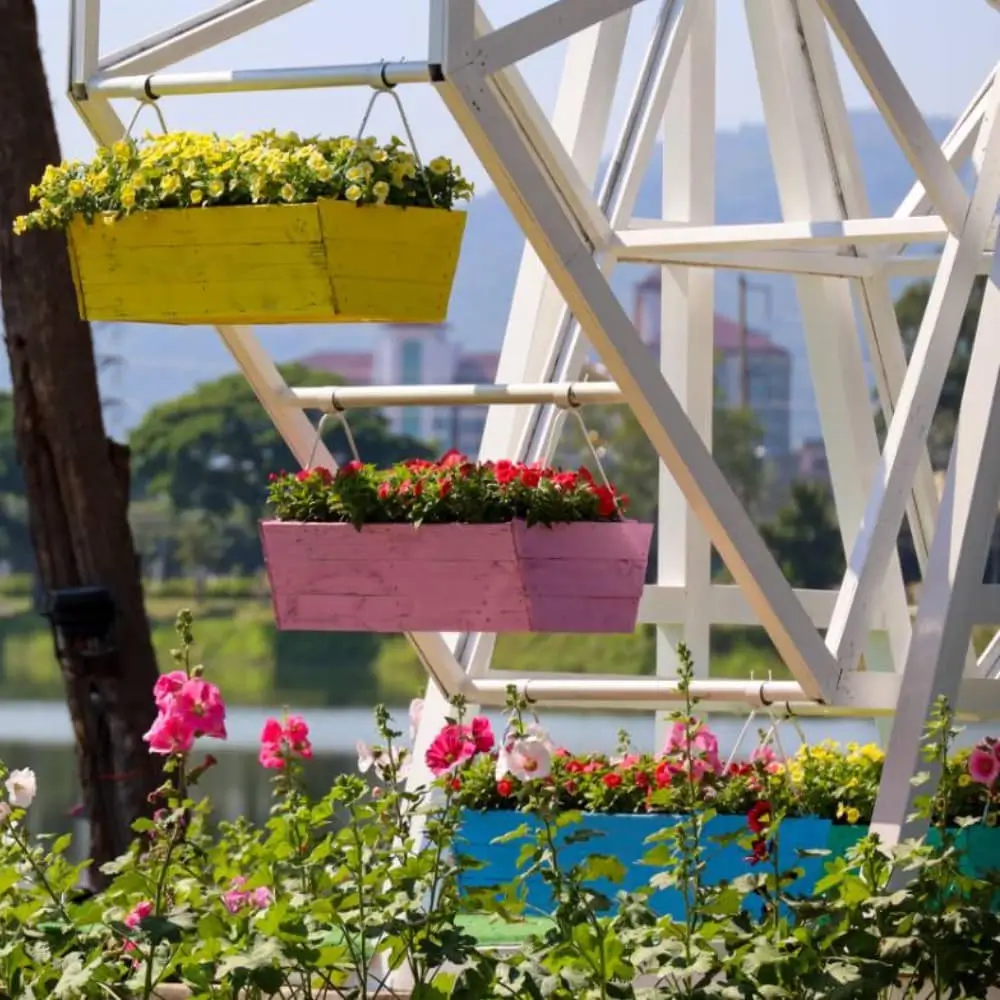 A close-up of a decorative Ferris wheel structure with colorful planter boxes holding vibrant flowers.