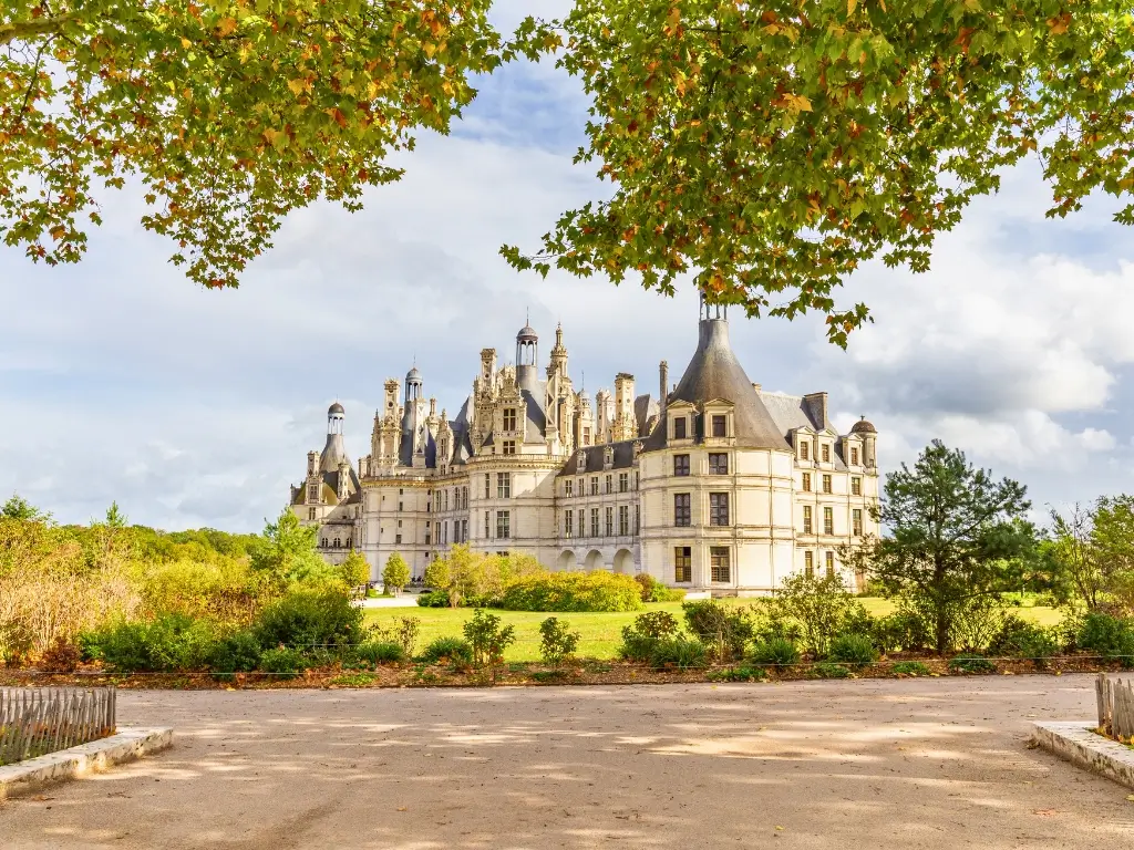 Château de Chambord in the Loire Valley, an iconic Renaissance castle with multiple towers and chimneys, framed by autumn leaves. This majestic sight is a prime example of the destinations reachable by day train trips from Paris.