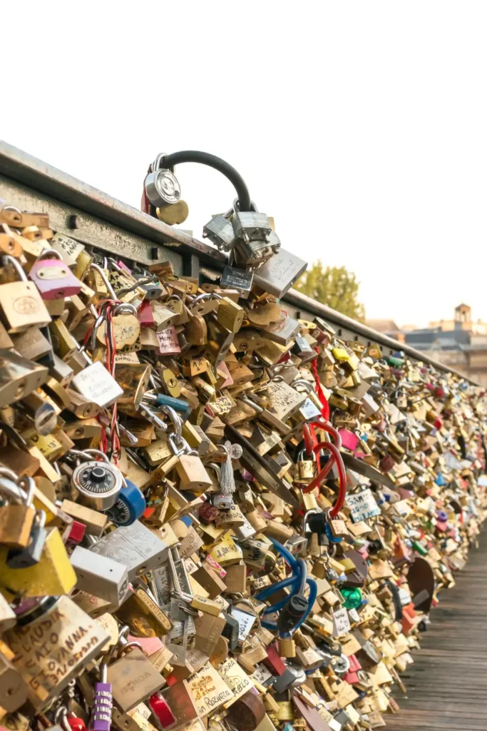 A dense collection of 'love locks' on a Parisian bridge railing, Pont des Arts, symbolizing love and commitment, with a blurred background highlighting the significance of the tradition.