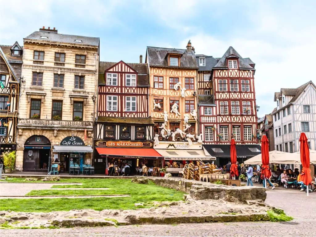 A lively square in Rouen with traditional half-timbered houses, bustling cafés, and open-air dining areas. Known for its rich history and medieval architecture, Rouen is a charming day trip from Paris by train.