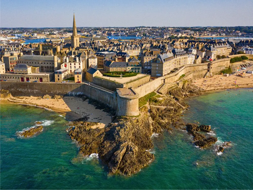 Aerial view of Saint-Malo, a picturesque coastal town in France and a top choice for the best day trips from Paris by train, with its historic walled city, sandy beach, and turquoise sea.