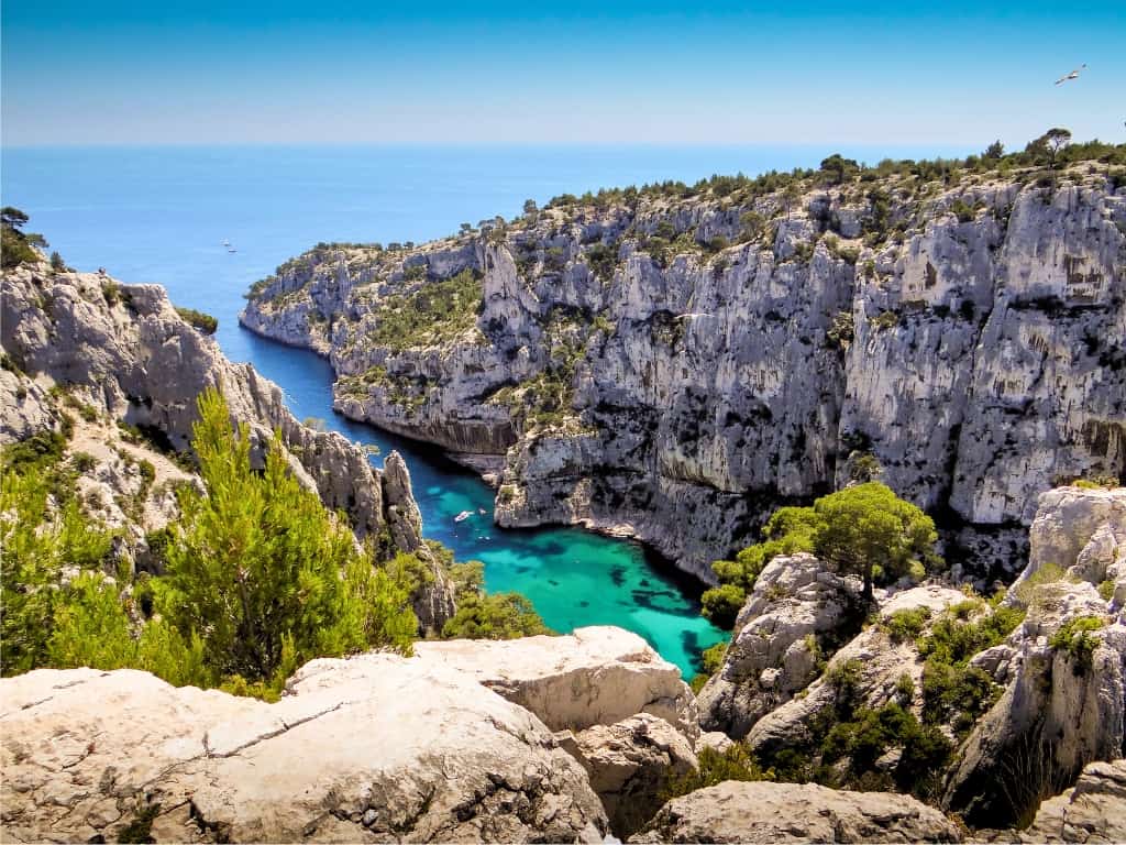 The Calanques of Cassis, where rugged white limestone cliffs drop sharply into the turquoise Mediterranean Sea. Accessible from Marseille, this natural wonder is a highlight for those taking a longer day trip from Paris by train and seeking breathtaking coastal scenery.