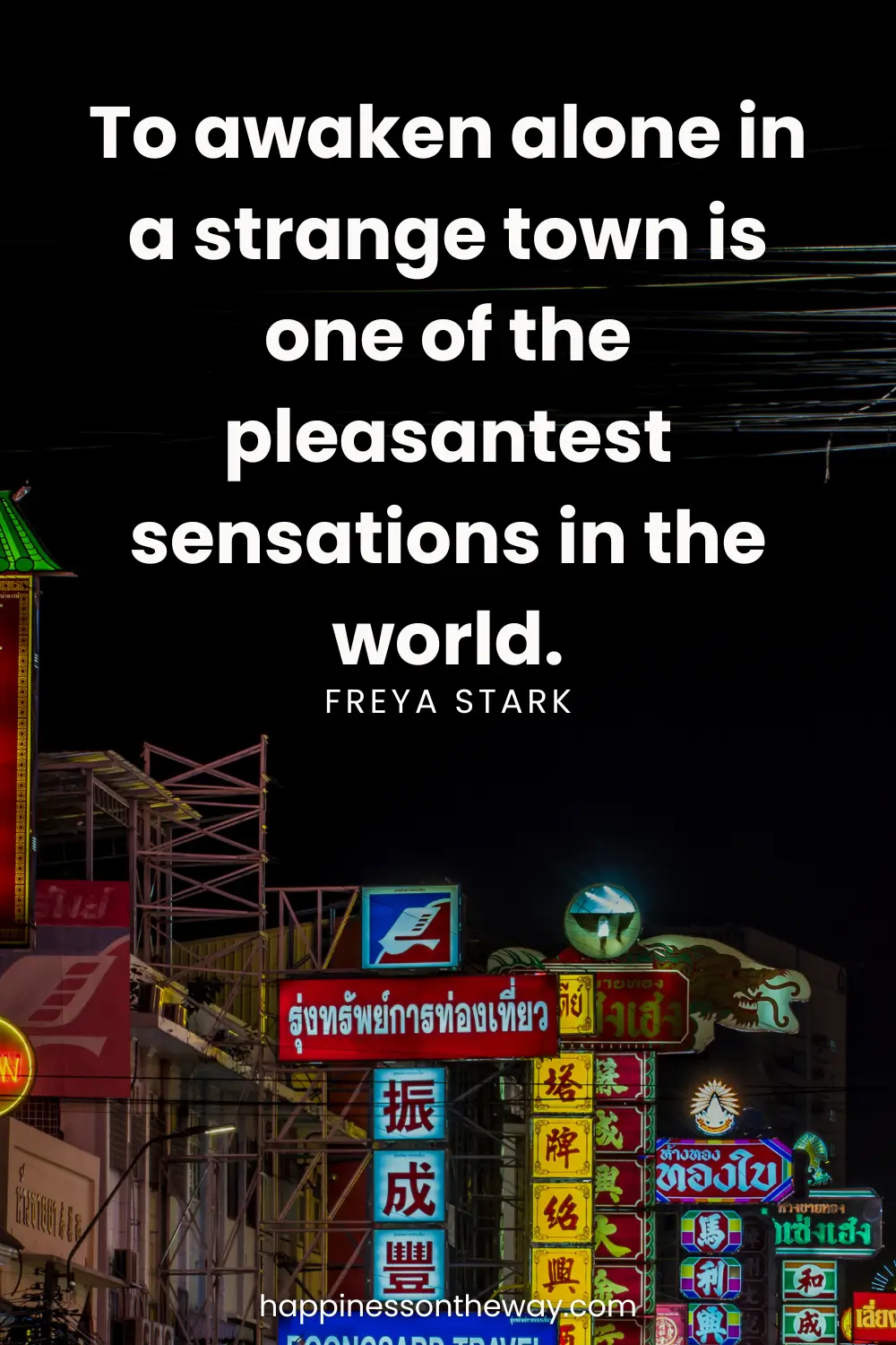 Vibrant street signs at night in an urban setting with the quote 'To awaken alone in a strange town is one of the pleasantest sensations in the world.' by Freya Stark