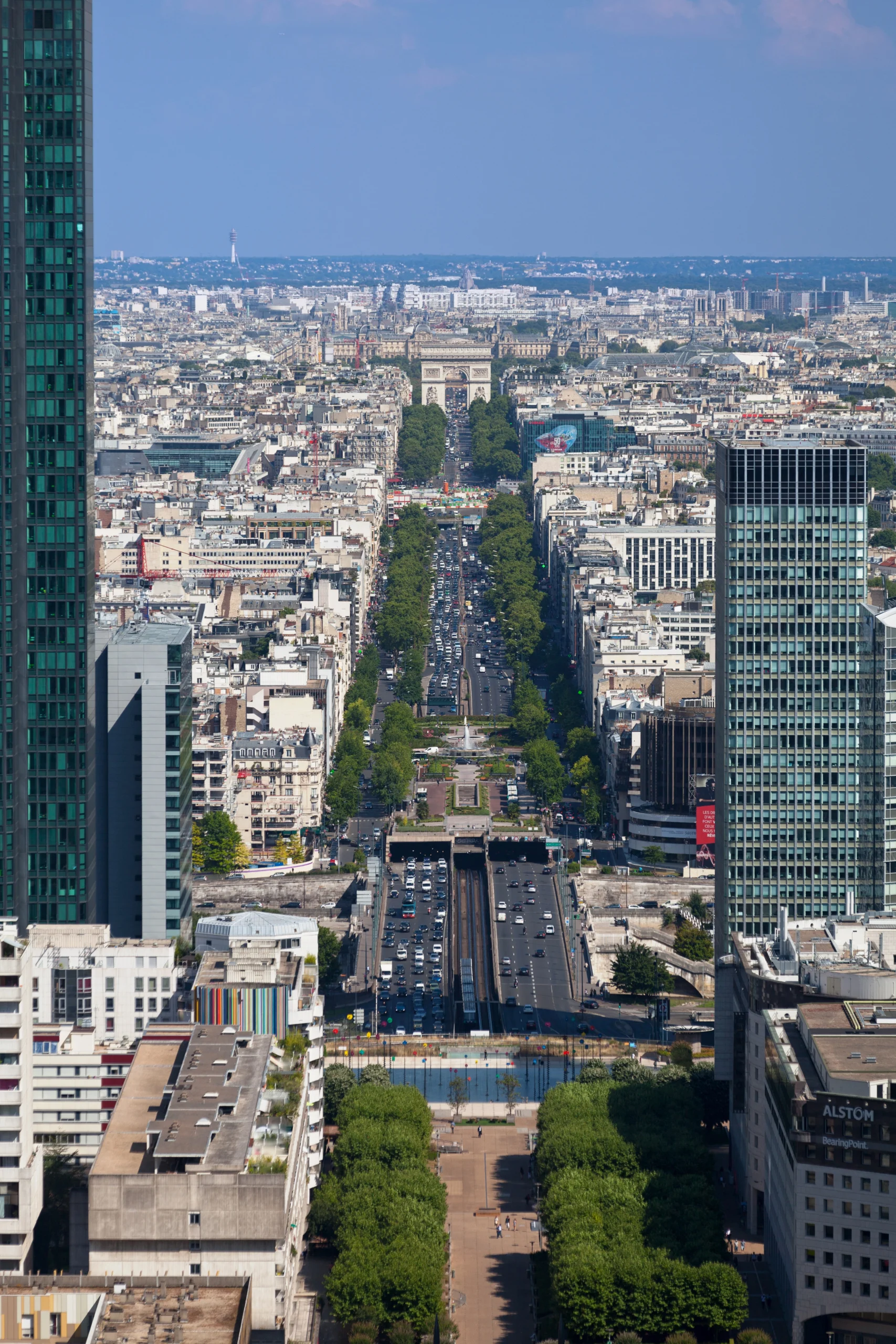 View from the terrace at the Grande Arche de la Défense in Paris, looking down a busy promenade with the best views of Paris towards the distant Arc de Triomphe and modern skyscrapers.