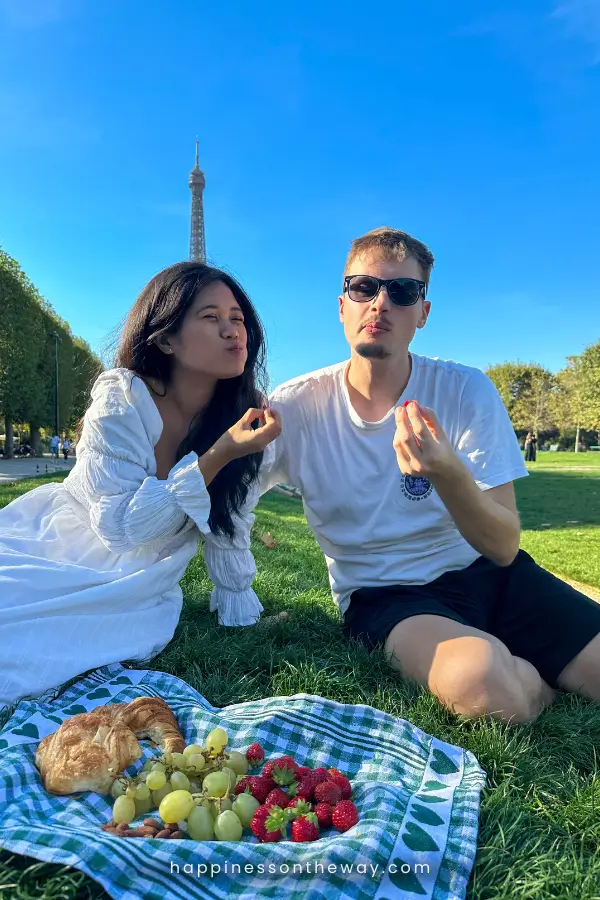 Mat and I enjoying a picnic at Champ de Mars, one of the best parks in Paris to picnic. With the Eiffel Tower in the background while surrounded by a spread of croissants, grapes, and strawberries on a checkered cloth.
