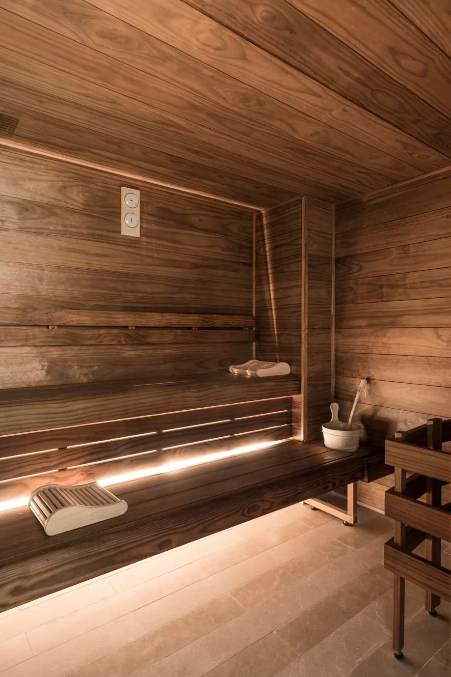 A tranquil sauna room at Grand Powers Paris, an eco-friendly hotel, featuring warm wooden panels, built-in bench seating, and soft lighting, creating a serene space for relaxation.