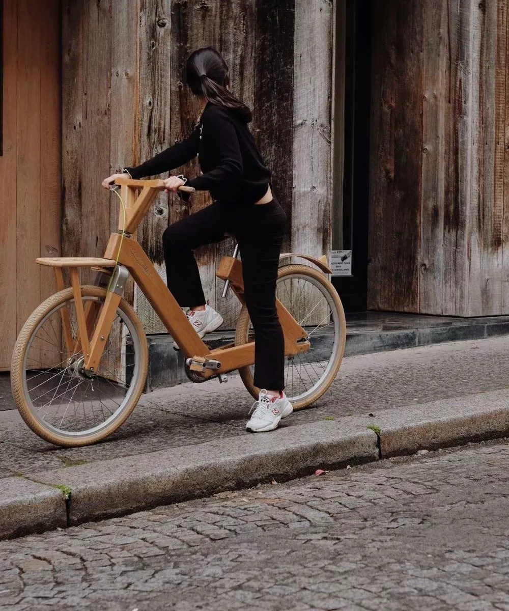 Guest at Hidden Hotel riding a stylish wooden bicycle on a cobblestone street in Paris, reflecting the hotel's commitment to eco-friendly transportation and active lifestyle.