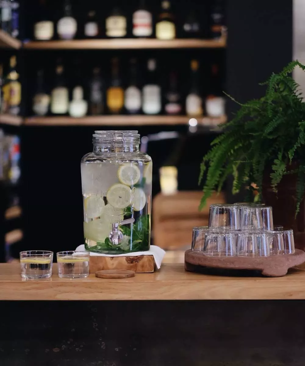 Sleek water dispenser with infused lemon water at Hidden Hotel in Paris, showcasing the hotel's dedication to offering sustainable, refreshing amenities to its guests.