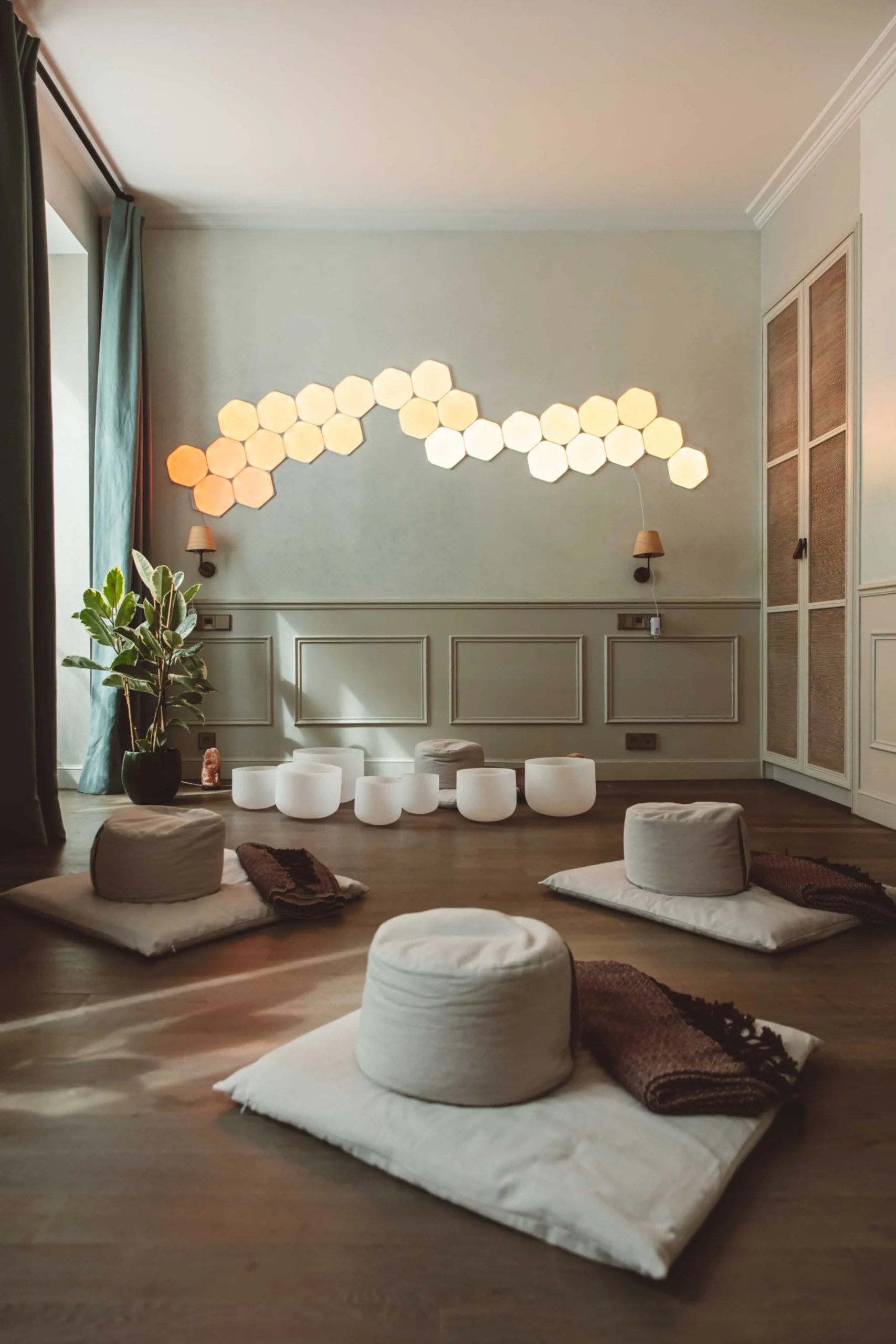 Serene meditation space at Home of Yoga (HOY) Hotel Paris, featuring a geometric light installation, floor cushions for mindfulness practice, and an ambiance conducive to eco-friendly relaxation.