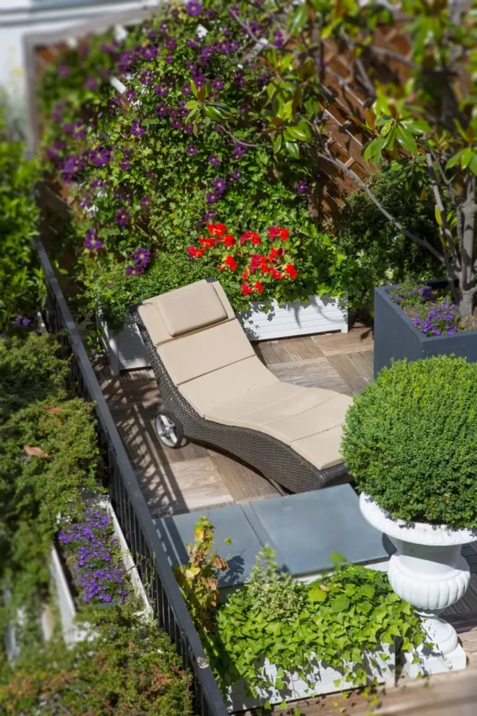 Peaceful garden terrace at Hotel Duc de Saint Simon in Paris, adorned with lush purple and red flowers and a relaxing sun lounger, highlighting the hotel's dedication to eco-friendly spaces.