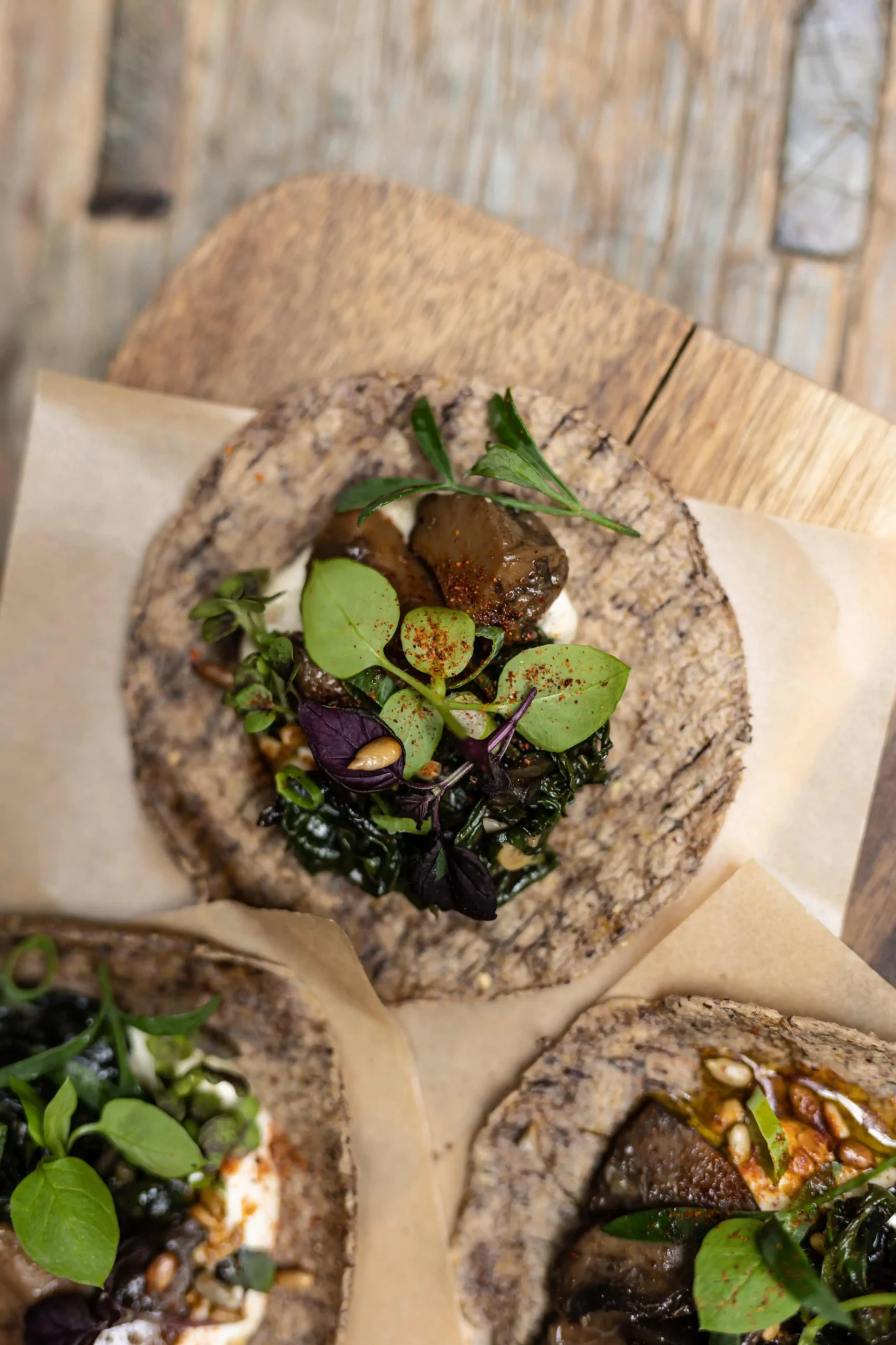 Sustainable dining at HOY Hotel Paris with a focus on organic food, showcasing buckwheat galettes topped with fresh greens, edible flowers, and a colorful sprinkle of spices.