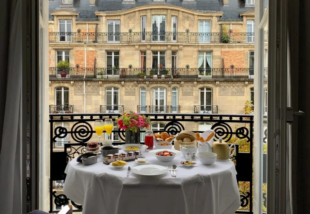Charming balcony dining at Hotel Lutetia in Paris, with a well-appointed breakfast table overlooking a classic Parisian street, offering an intimate al fresco dining experience.