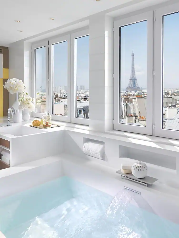 Luxurious bathroom with a large window at the Mandarin Oriental, an eco hotel in Paris, featuring a spacious bathtub with a serene view of the Eiffel Tower, embodying opulent relaxation.