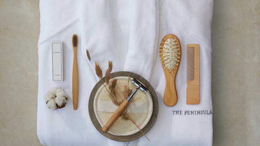 Eco-conscious bathroom amenities at Peninsula Paris, including a bamboo toothbrush, wooden comb, and biodegradable packaging, laid out on a soft towel, symbolizing the hotel's commitment to plastic-free luxury.