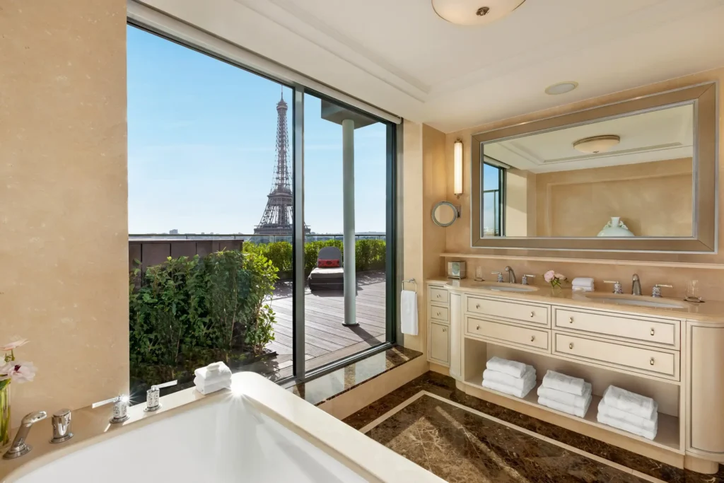 Elegant eco-luxury bathroom at Shangri-La Paris, featuring a bathtub with a panoramic view of the Eiffel Tower, marble accents, and sustainable amenities.