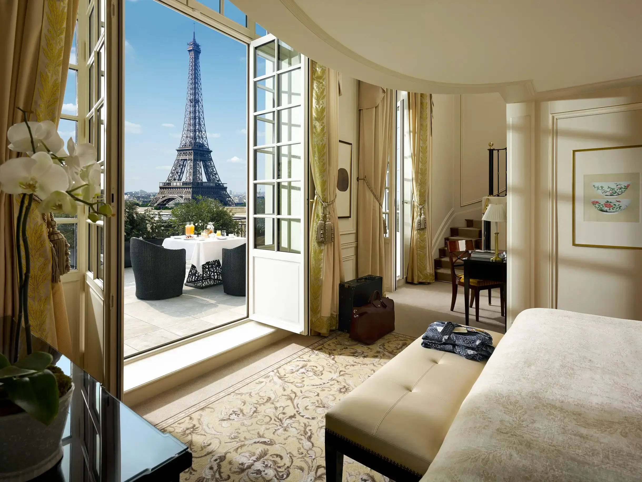 Stunning Duplex Terrace Eiffel View Suite at Shangri-La Paris, an eco-friendly hotel, with opulent furnishings and a balcony offering a breathtaking view of the Eiffel Tower.