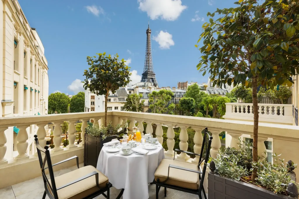 Gorgeous garden dining setup at Shangri-La Paris with a pristine white tablecloth, lush greenery, and the iconic Eiffel Tower in the background, exemplifying luxury in harmony with nature.