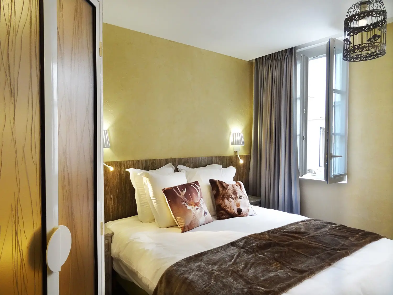 Sustainable elegance in Hotel Pavillon Paris' double room, with natural-toned decor, a plush bed featuring animal-themed pillows, and eco-friendly lighting.