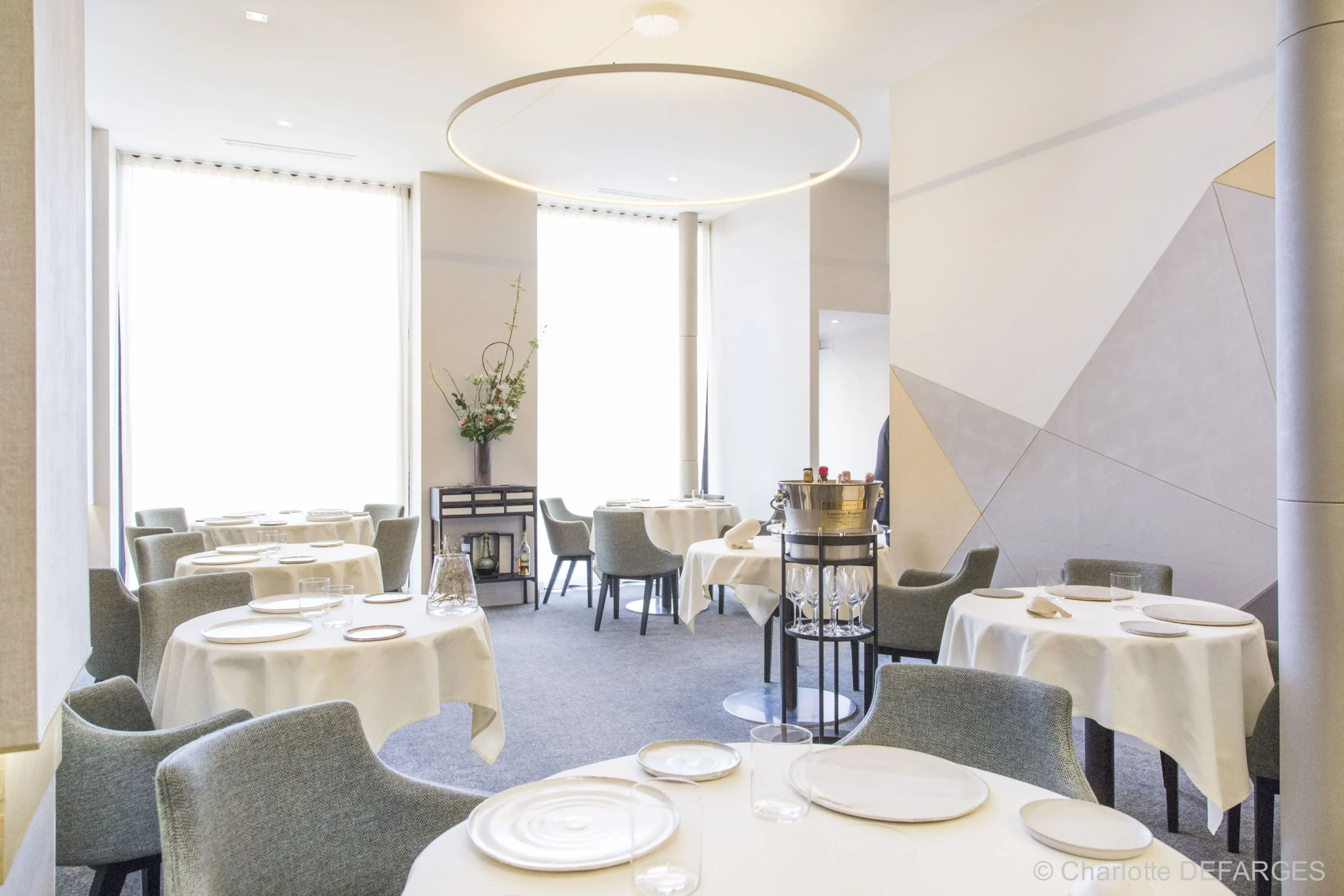 The serene and stylish dining room of Alliance Paris, known for being one of the most affordable Michelin Star restaurants in Paris, bathed in natural light with a modern and airy decor, ready to welcome diners to a luxurious yet accessible experience.