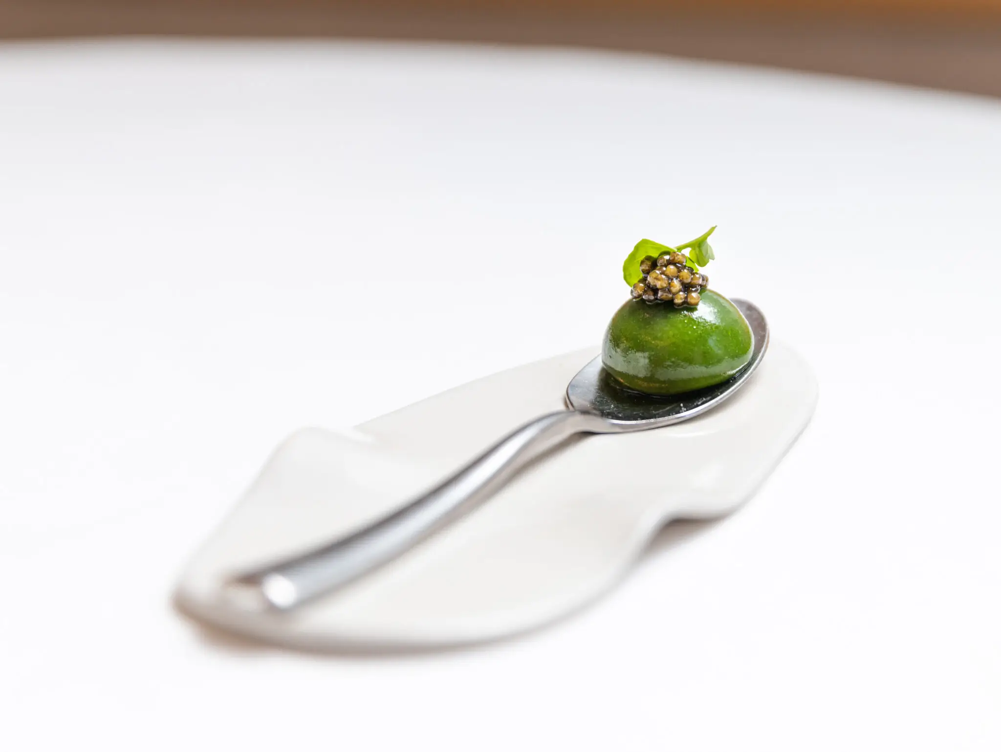 A sophisticated appetizer at Alliance in Paris, featuring a vibrant green watercress amuse-bouche topped with caviar, presented on a sleek spoon – a testament to the affordable luxury of Michelin-star dining.