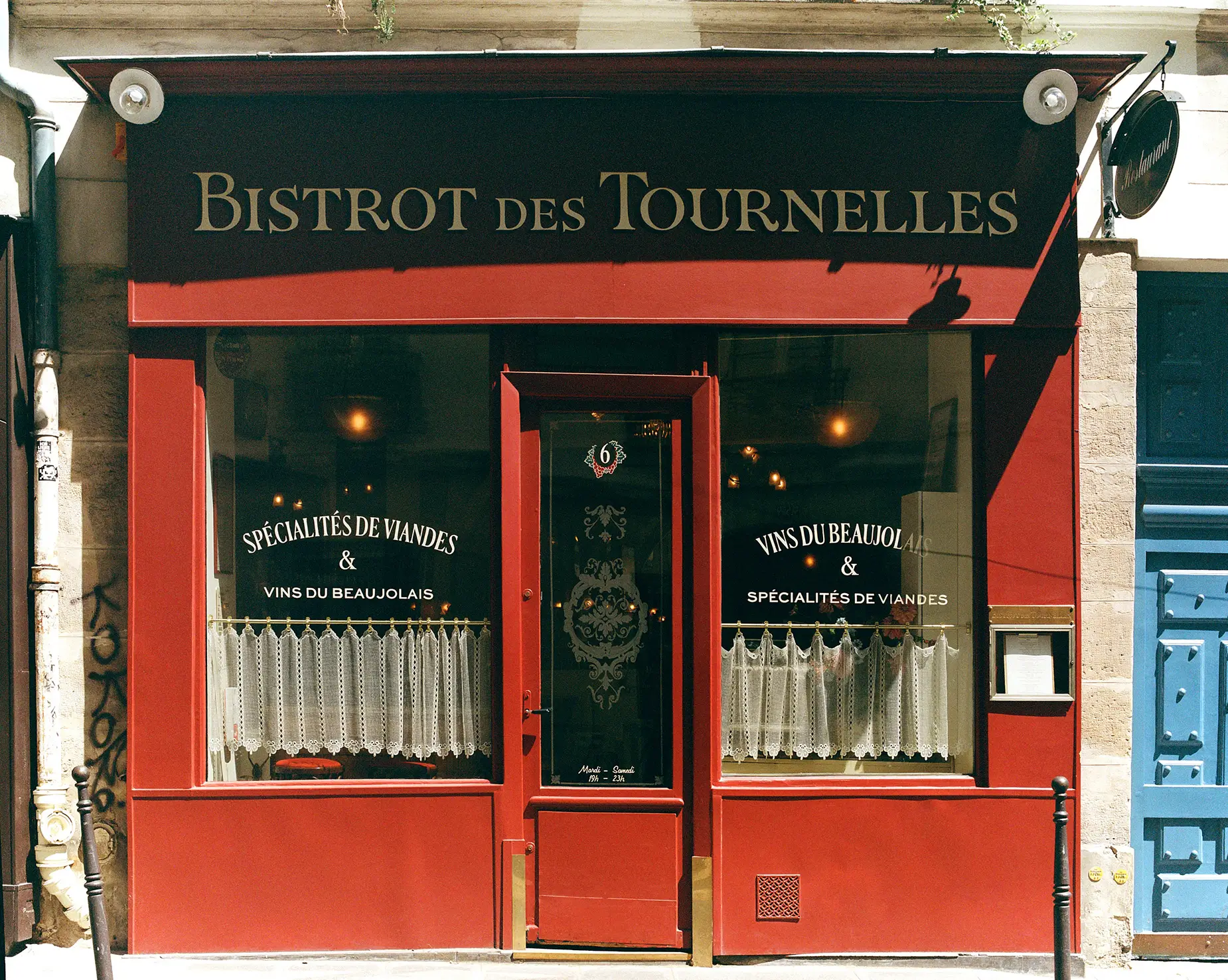 he vibrant red facade of Bistrot Des Tournelles in Paris, with a sign advertising 'Vins du Beaujolais' and 'Spécialités de Viandes.
