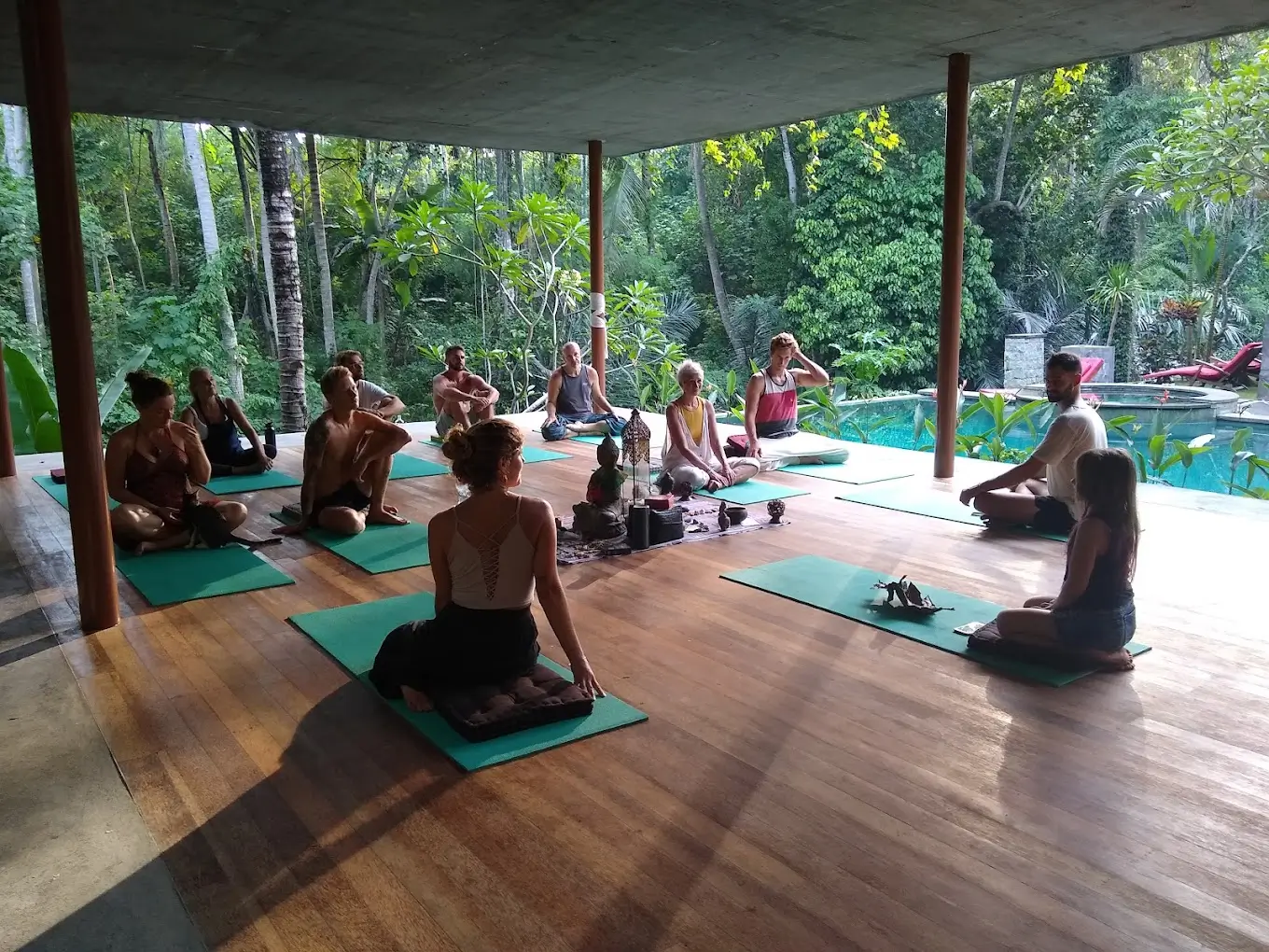 Participants sitting on mats in a discussion circle with a meditation guide at HUOMN Retreat in Bali