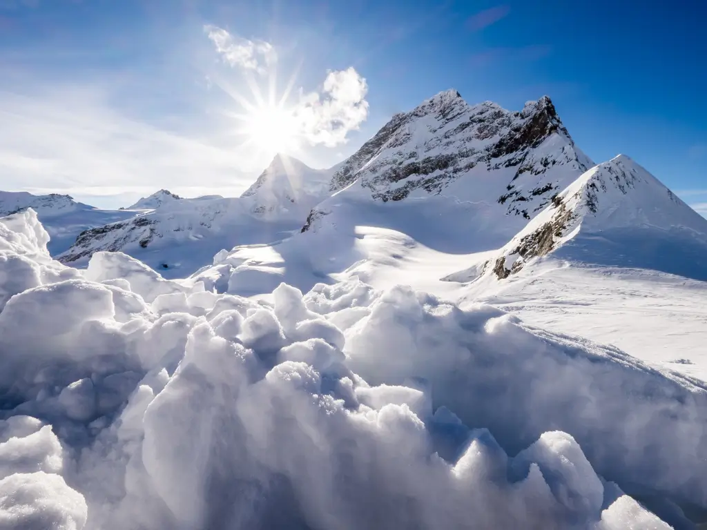The sun casts a radiant glow over the pristine snowfields and rugged peaks of Jungfraujoch, Switzerland 'Top of Europe'.