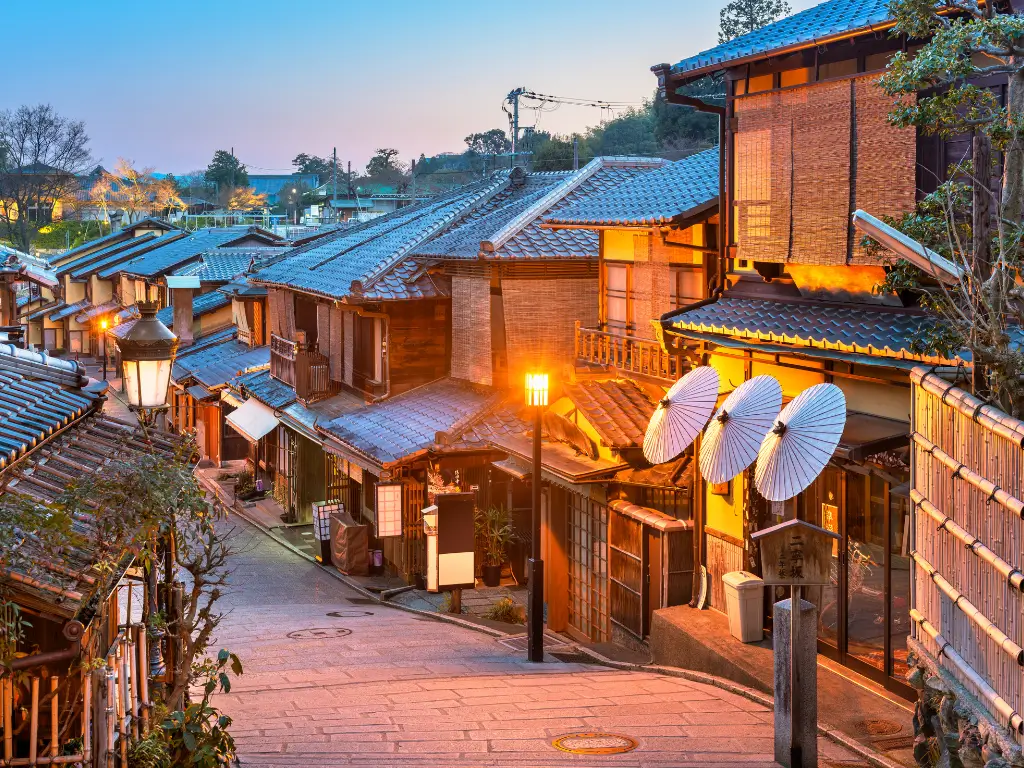 Historic street in Kyoto, Japan, at dusk with glowing lanterns and traditional wooden architecture, reflecting the serene spirit of slow travel destinations.