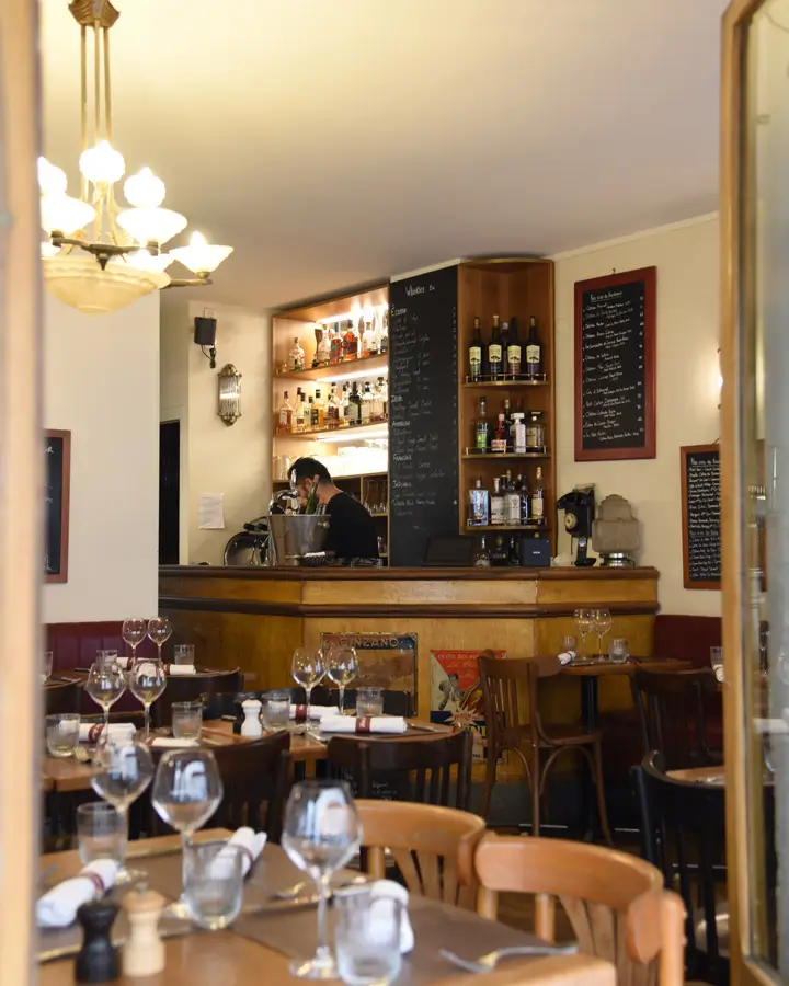 Cozy interior view of Le Petit Pontoise, featuring a well-stocked bar and chalkboard menus, creating an inviting atmosphere typical of a Parisian bistro.