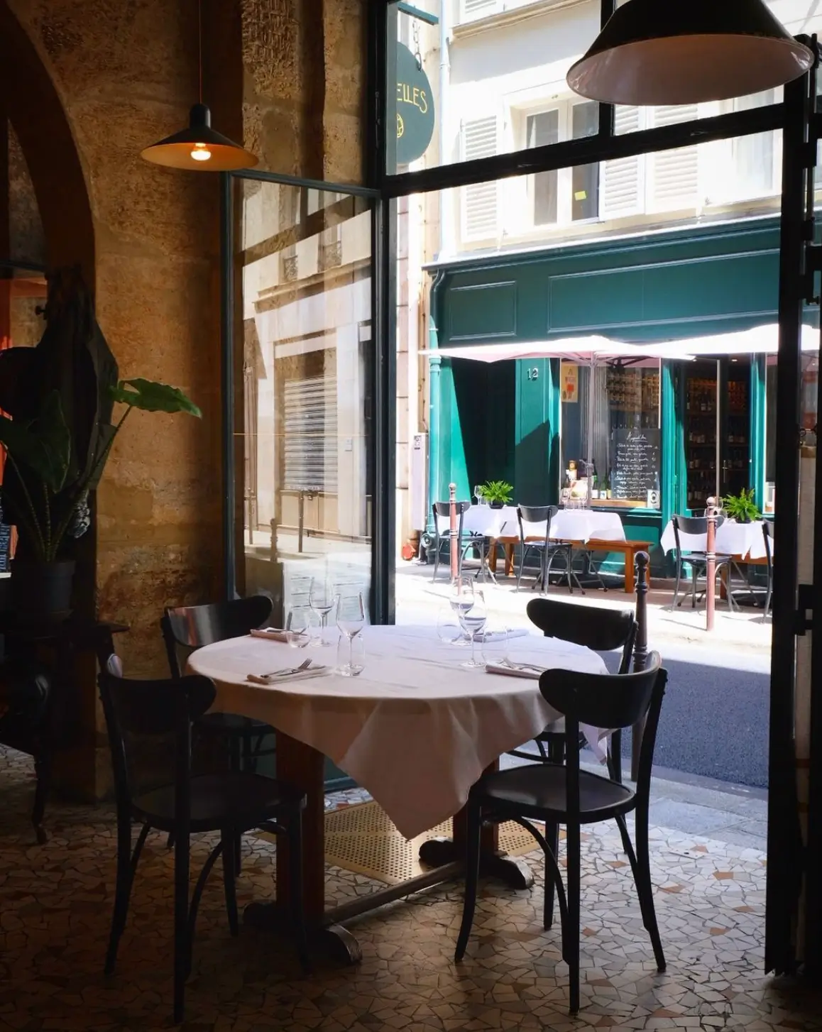 A charming table setup at Parcelles Bistro in Paris, positioned by an open window with a street view, inviting a quintessentially Parisian dining experience.
