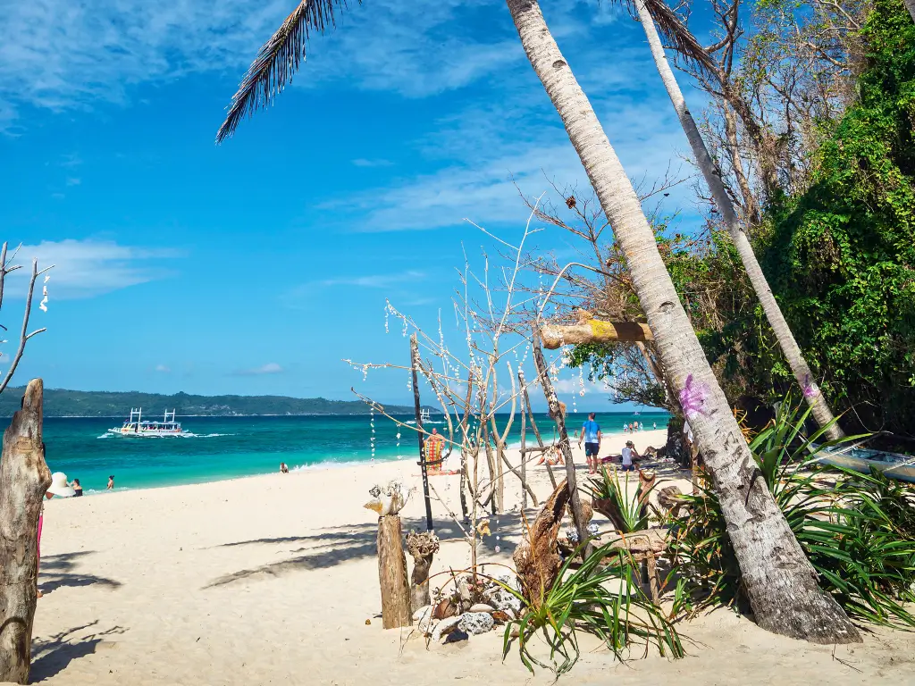 raditional Filipino boats line the shore of Puka Beach in Boracay, set against a backdrop of clear skies and azure waters, a natural gem among Boracay land tour destinations.