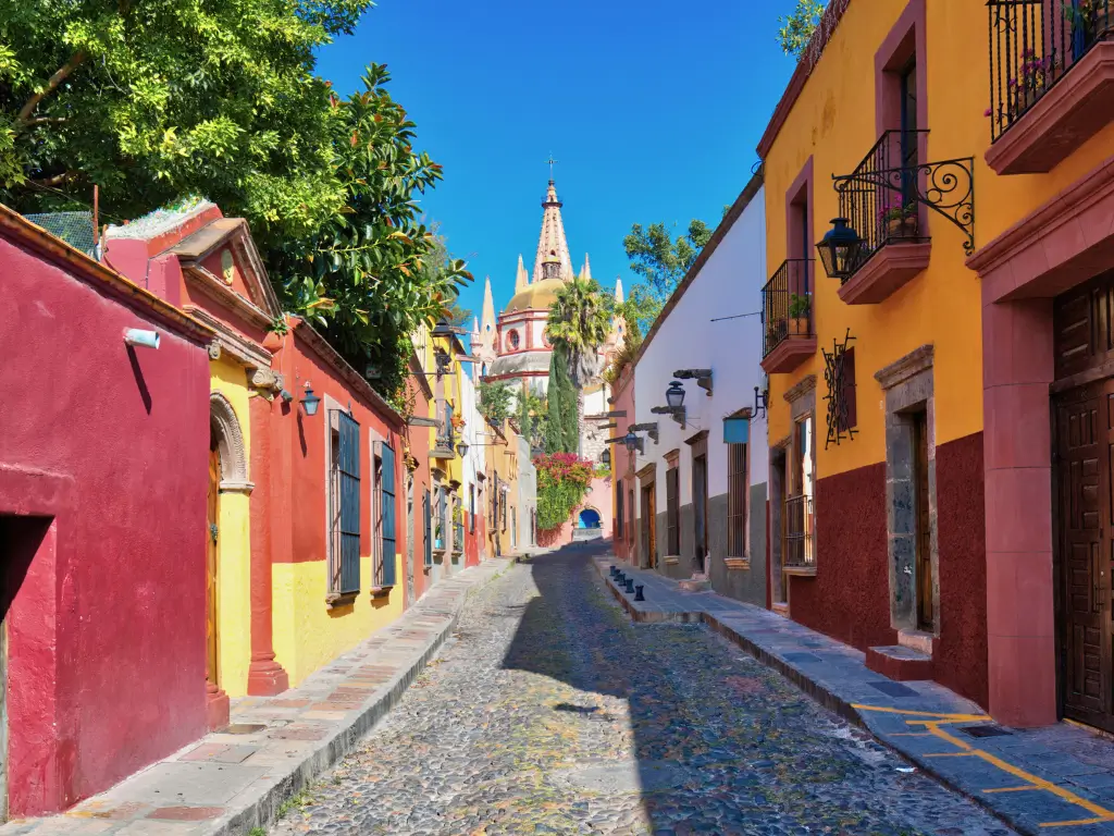 Colorful colonial architecture lining a cobblestone street in San Miguel de Allende, Mexico, capturing the essence of slow travel destinations.