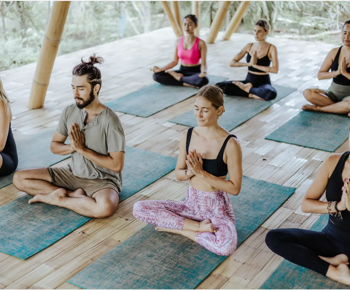 Participants in a serene meditation pose during a yoga class at Surf & Yoga Canggu