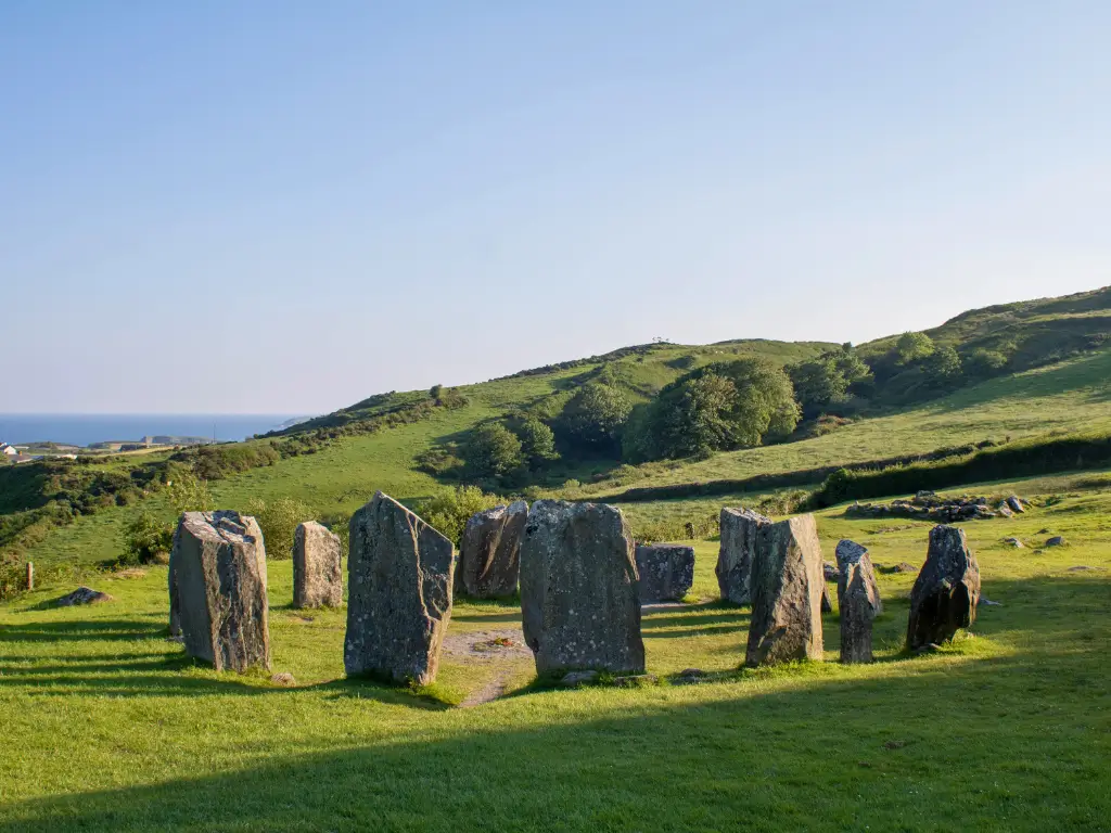 Ancient stone circle in lush greenery with distant sea views in West Cork, Ireland, epitomizing serene slow travel destinations.