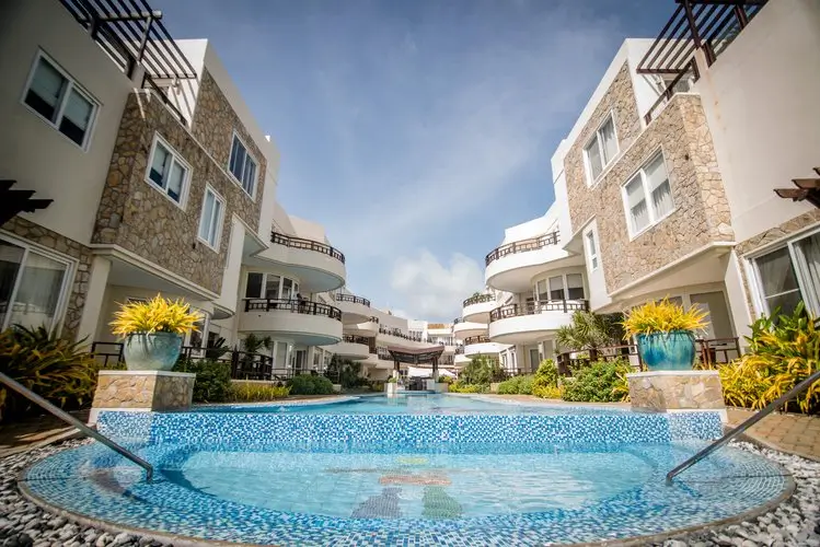 Charming courtyard pool area at 7Stones Boracay, featuring a mosaic-tiled circular pool surrounded by stone-clad buildings with balconies and tropical landscaping.
