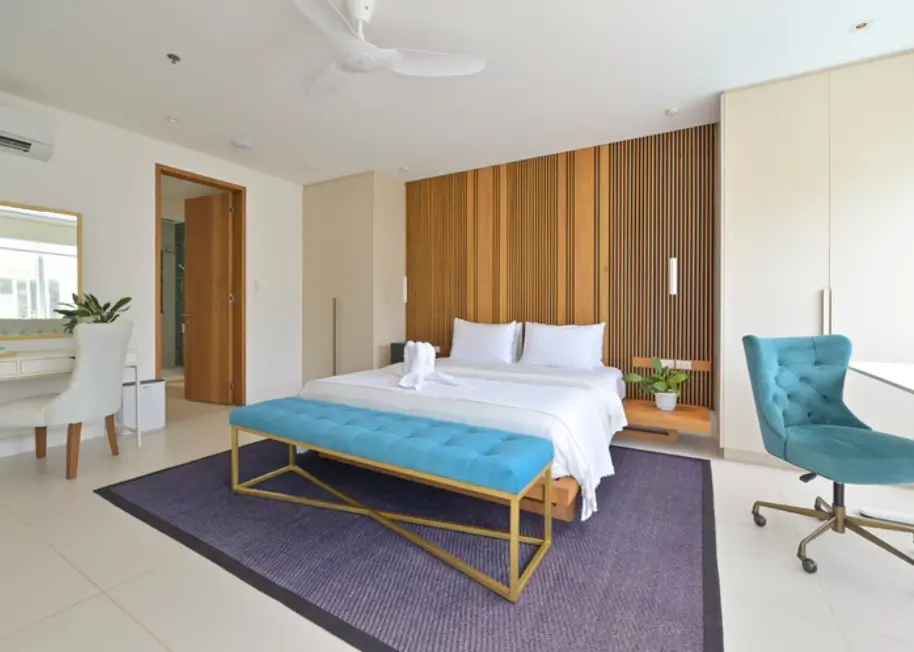 Minimalist and elegant bedroom at 7Stones Boracay, a boutique hotel. The room is decorated with a large bed, wooden wall paneling, and soft lighting, creating a serene ambiance.