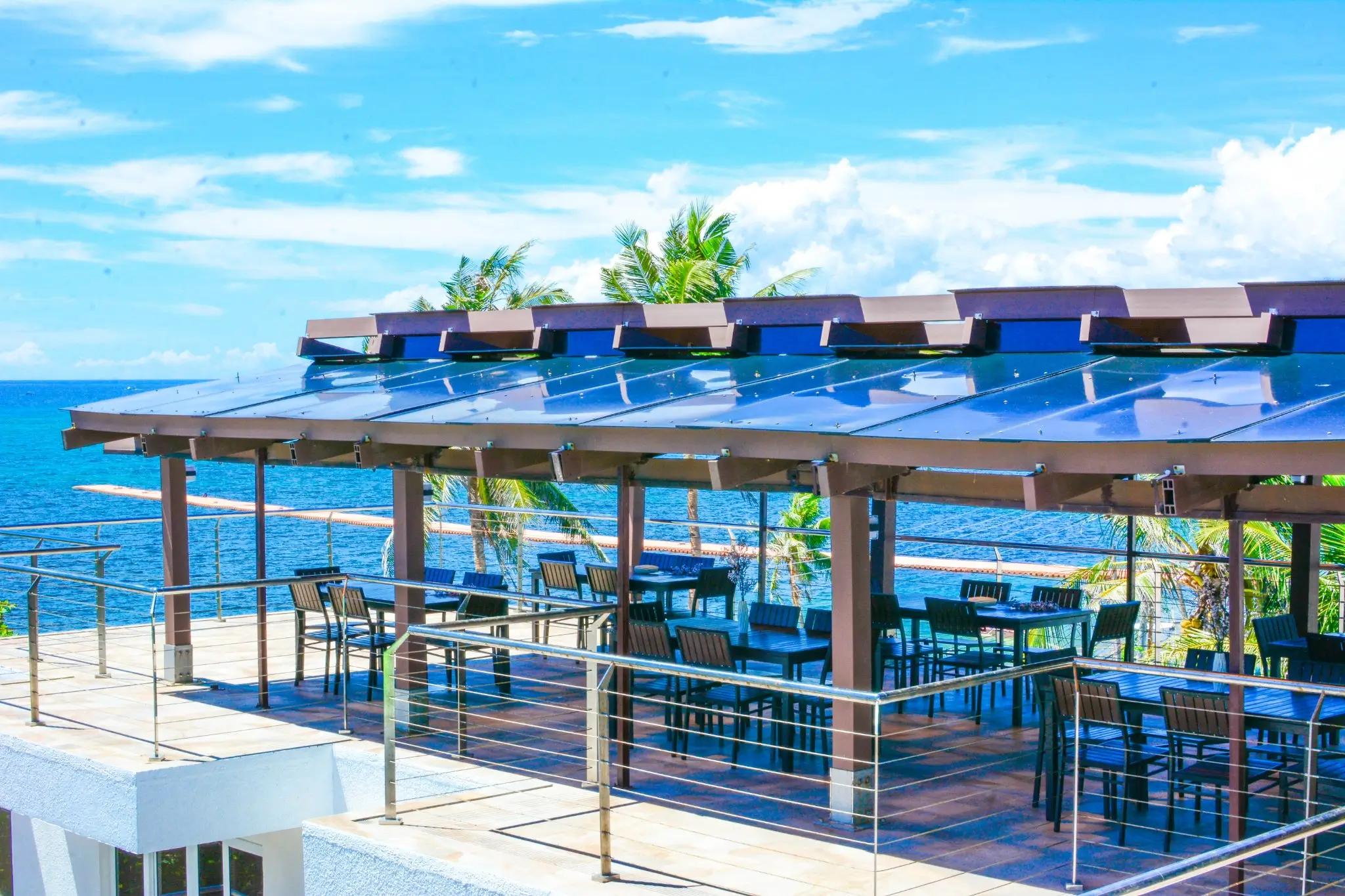 Open rooftop dining area at Aira Boracay, a boutique resort in Boracay, offering unobstructed views of the ocean. The area is equipped with modern furniture under stylish pergolas, ideal for a seaside dining experience.