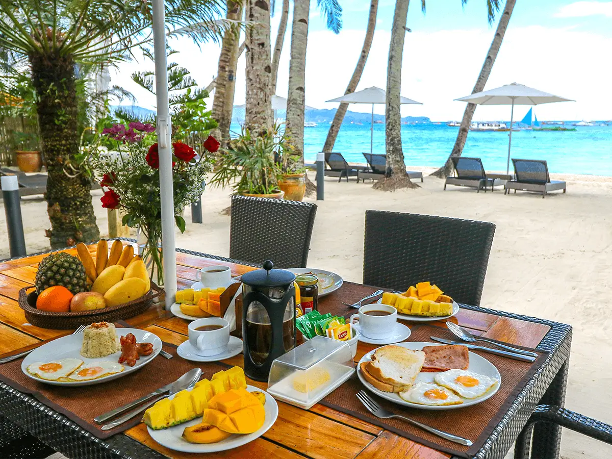 Beachfront dining setup at Boracay Beach Houses Boutique Hotel, with a full breakfast spread overlooking the scenic Boracay beach and azure waters.