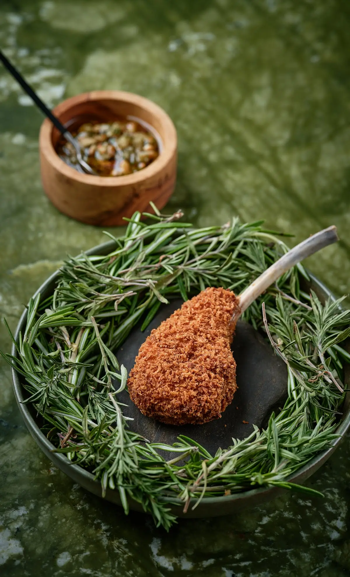 Breaded lamb chop surrounded by fresh rosemary at Contraste, a Michelin Star restaurant in Paris.