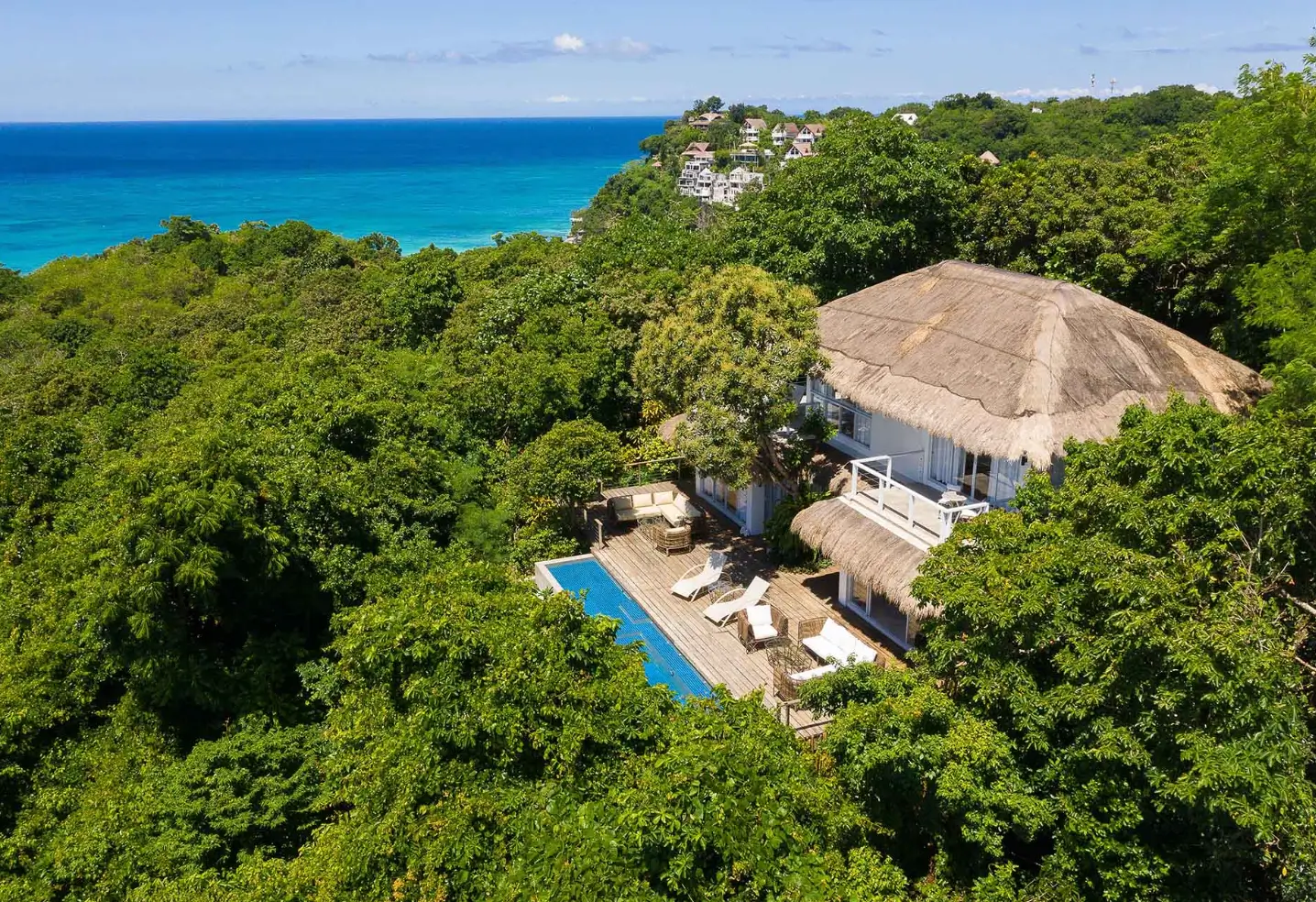Aerial view of Diniview Villa Resort, a boutique resort in Boracay. The villa, with its thatched roof, is surrounded by dense greenery and has a private pool overlooking the turquoise sea.