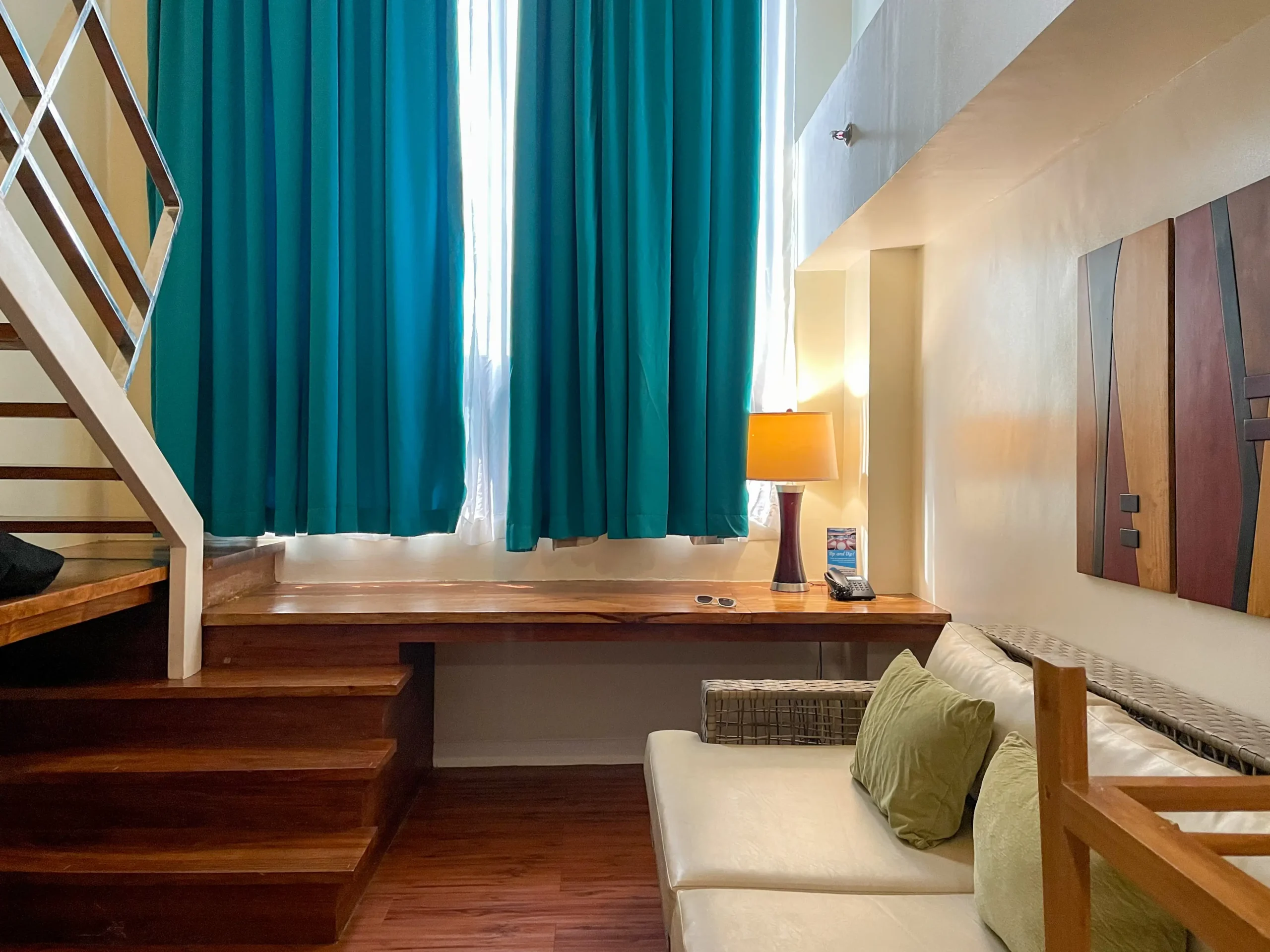 Cozy corner of a suite in Ferra Hotel and Garden Suites in Boracay with a two-level seating area, hardwood floors, and vibrant teal curtains.
