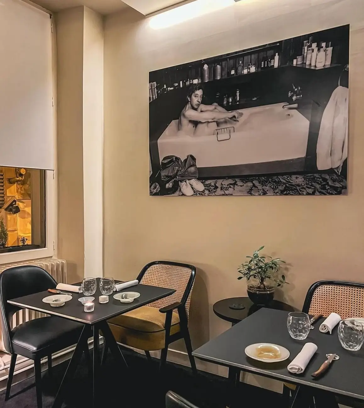 Cozy dining area at Fleur de Pavé in Paris, featuring a black and white photo of a person in a bathtub on the wall.