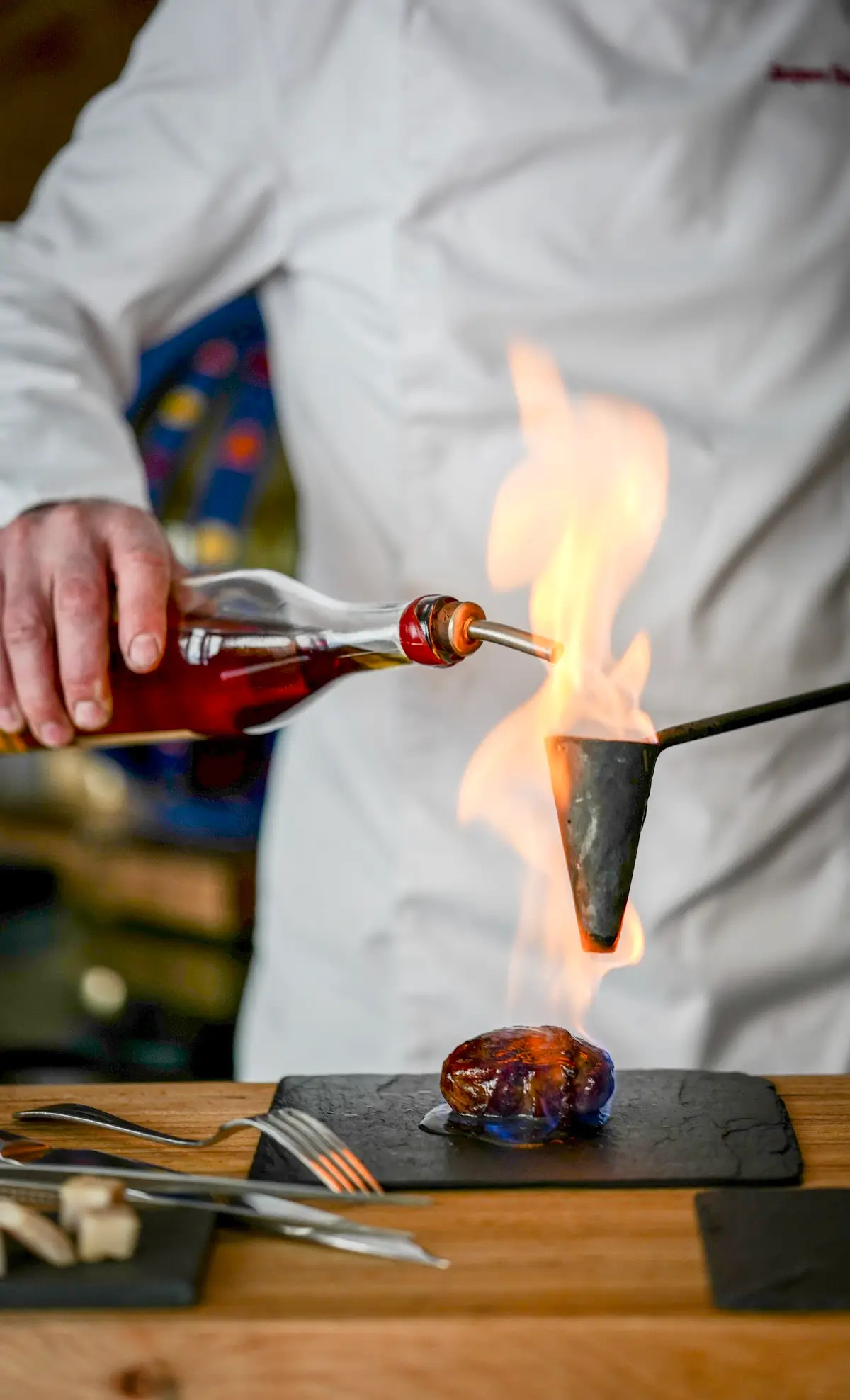 Chef using a torch to caramelize food at Jacques Faussat, a Michelin Star restaurant in Paris.
