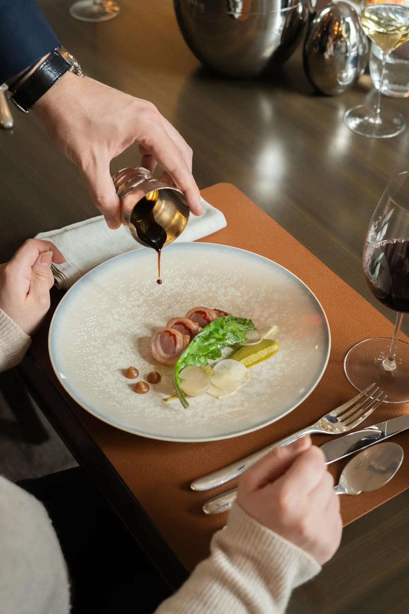 Server pouring sauce over a plated dish at Restaurant Trente-Trois, a Michelin Star restaurant in Paris