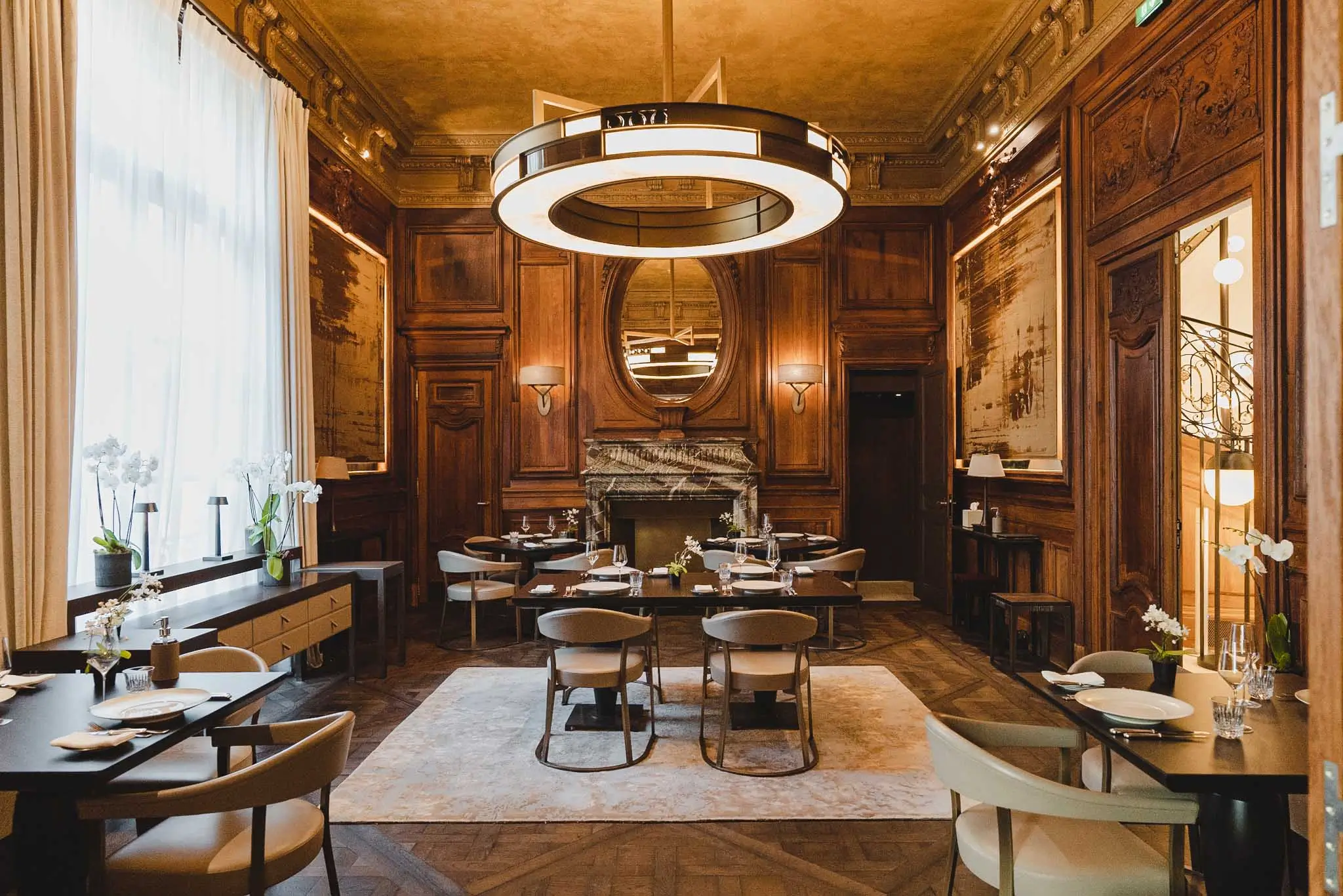 Luxurious dining room with wooden paneling and large chandelier at Restaurant Trente-Trois, a Michelin Star restaurant in Paris.